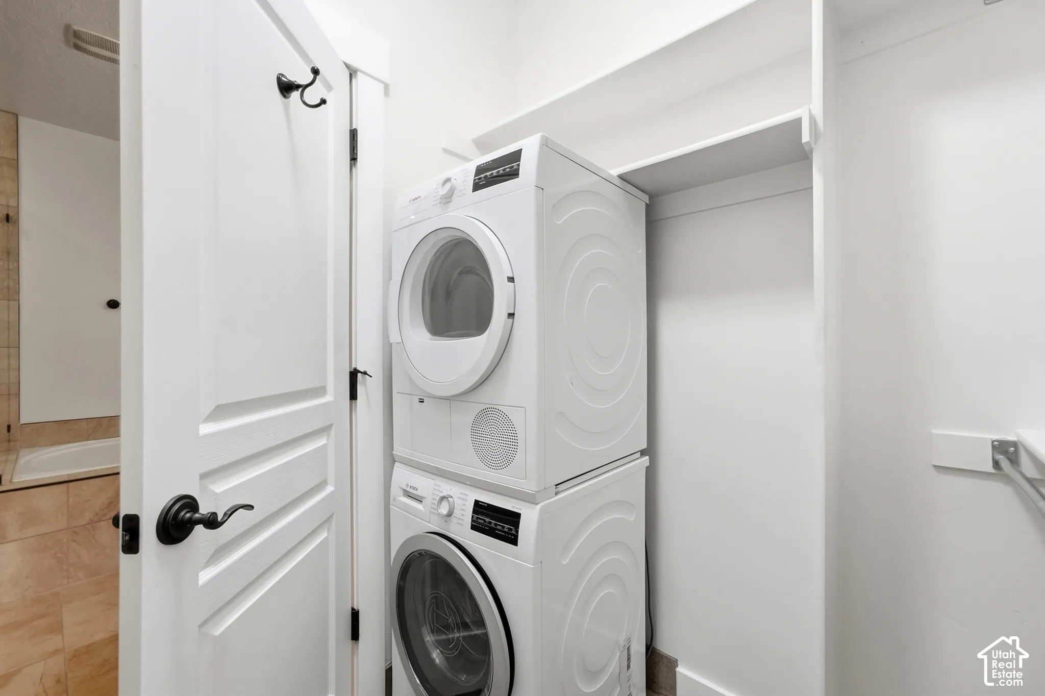Stackable washer and dryer, built-in shelving, white paneled door with dark hardware