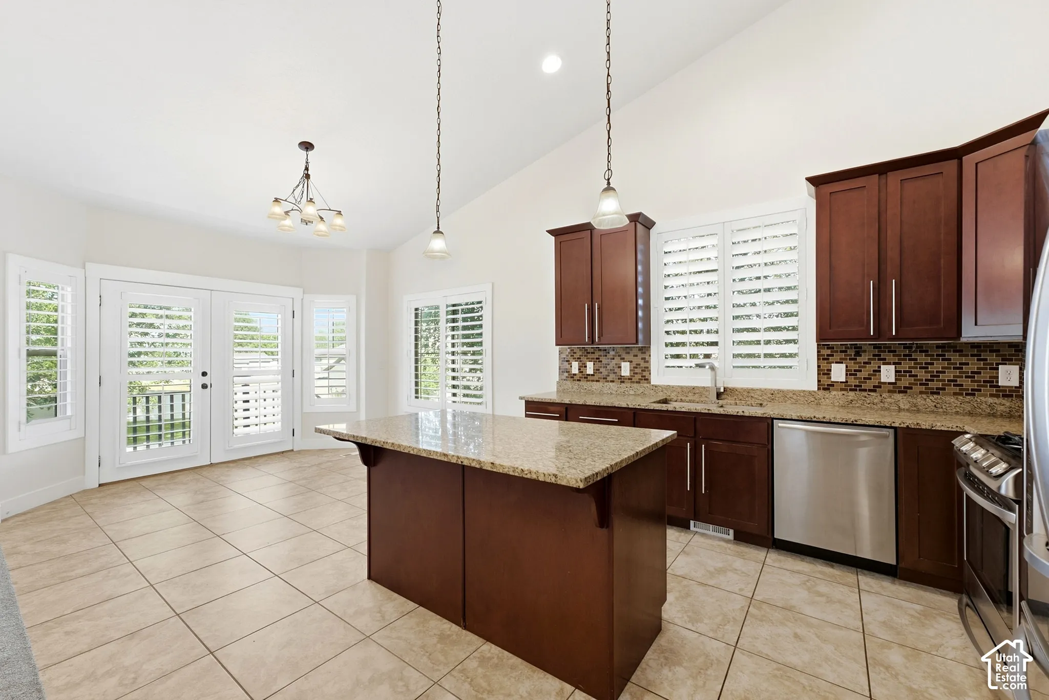 Kitchen featuring an island with stone countertops, dark wood cabinetry, stainless steel appliances, and a mosaic tile backsplash