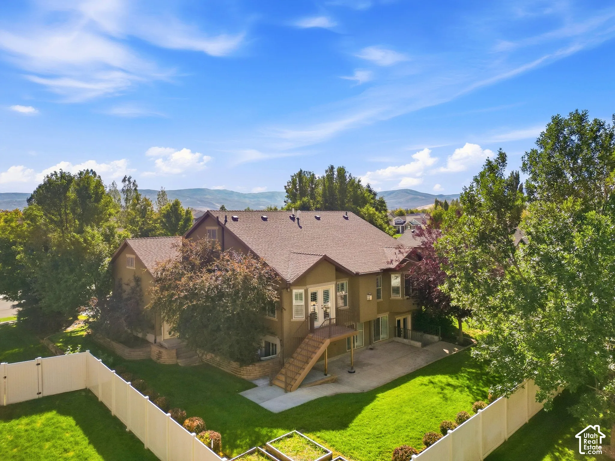 Expansive backyard featuring a manicured lawn, mature trees, and a spacious patio