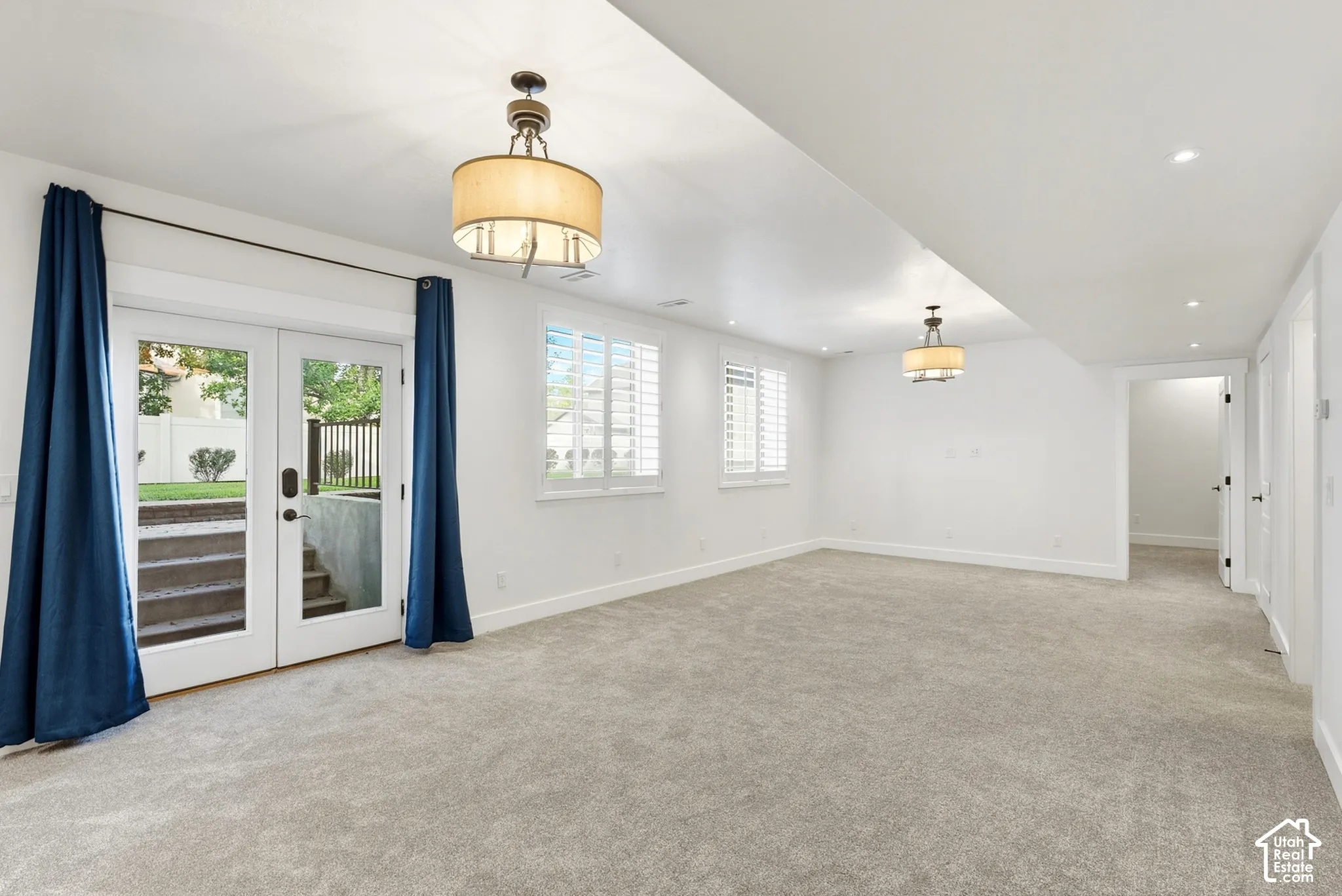 Wall-to-wall carpeting and white walls define this bright space, featuring white double doors with exterior access