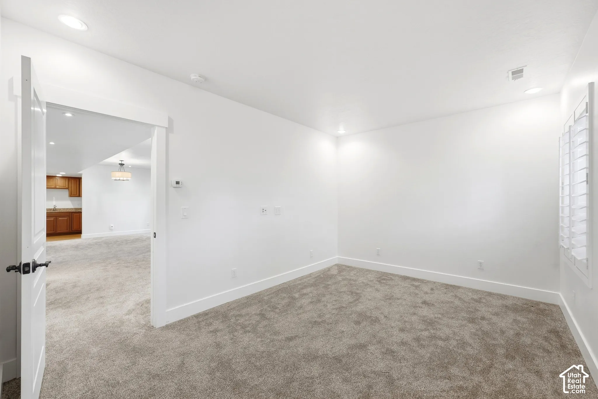 Carpeted room with white walls, recessed lighting, and window with white shutters