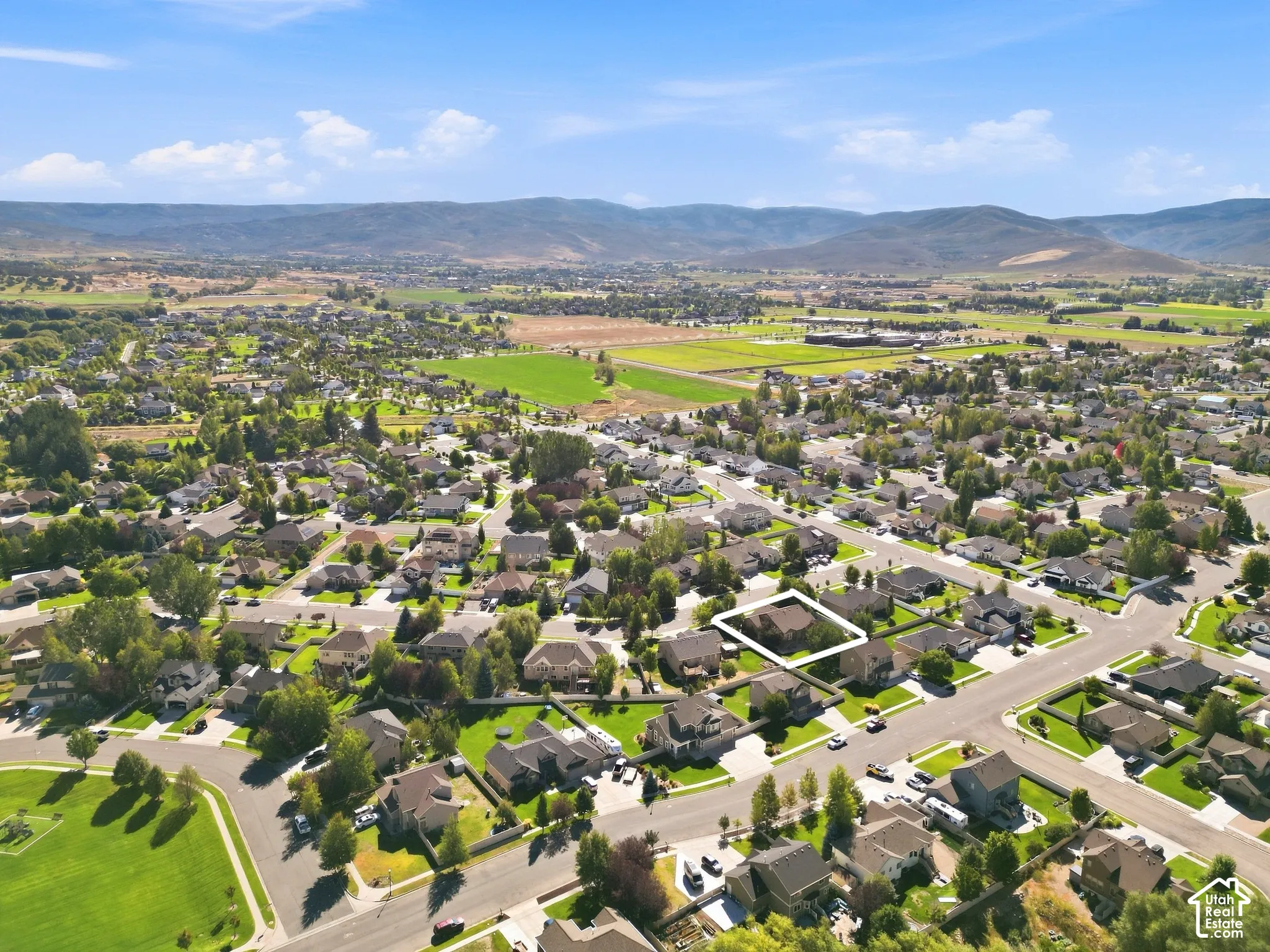 Residential neighborhood with mature trees, surrounded by distant mountains and open green spaces