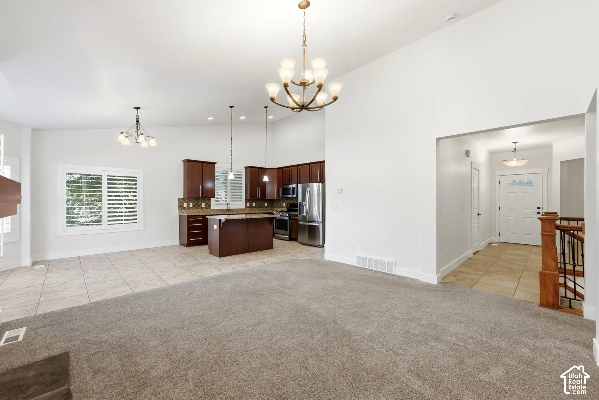 Vaulted ceilings with chandelier lighting, dark wood cabinetry, stainless steel appliances, and a kitchen island with bar seating