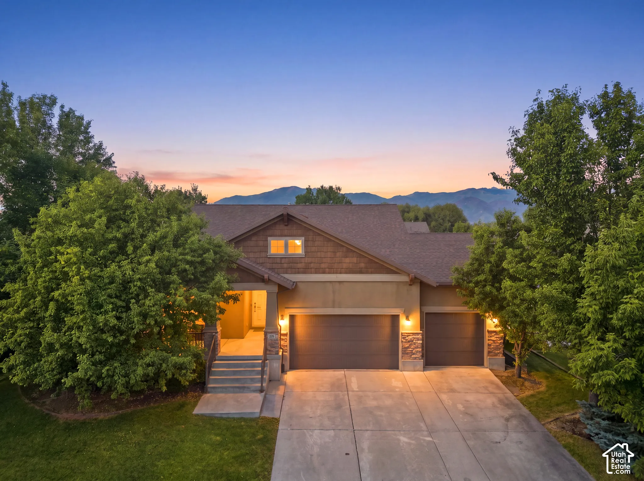 Contemporary residence featuring a shingle roof, stone accents, and a multi-car garage