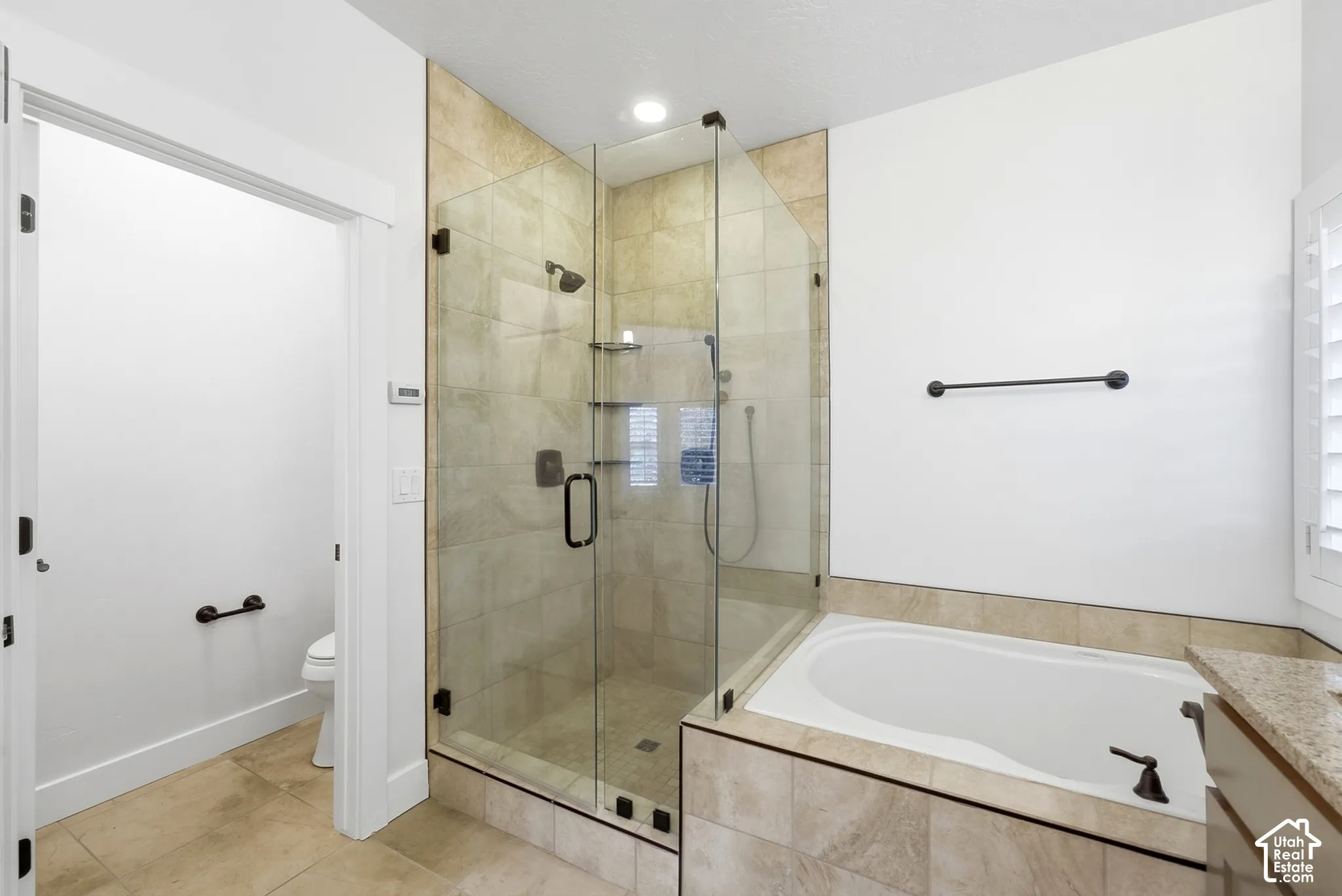 Glass-enclosed shower with tiled surround, built-in shelving, and dark bronze fixtures
