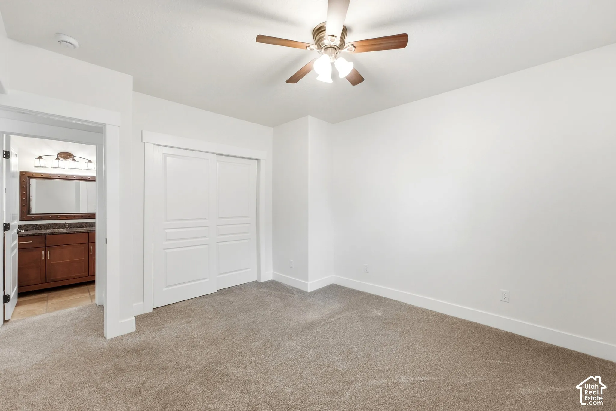 Carpeted bedroom with a ceiling fan, sliding closet doors, and recessed lighting