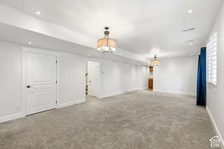 Spacious room with plush gray carpeting, recessed lighting, and two drum pendant light fixtures