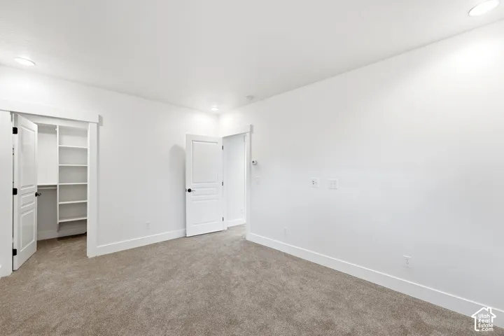 Plush carpet flooring, integrated recessed lighting, and a built-in closet with shelving