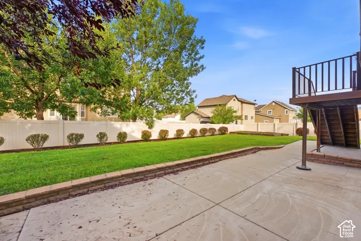Expansive backyard featuring a lush lawn, concrete patio, and a privacy fence