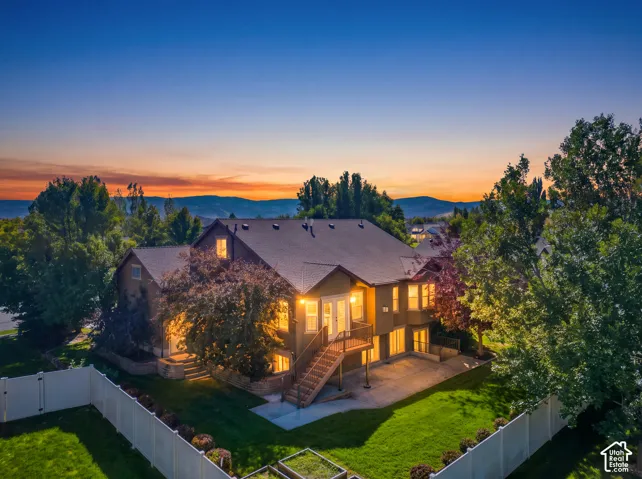 Expansive rear exterior with a pitched roofline, multi-level deck, concrete patio, and a manicured lawn