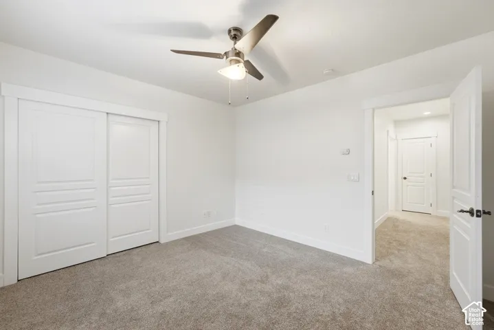 Neutral-toned carpeting, white walls, and a ceiling fan with integrated lighting