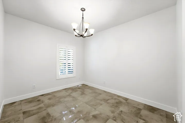 Recessed window with plantation shutters, overhead chandelier, and large format tile flooring