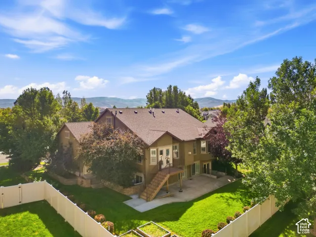 Expansive backyard featuring a manicured lawn, mature trees, and a spacious patio