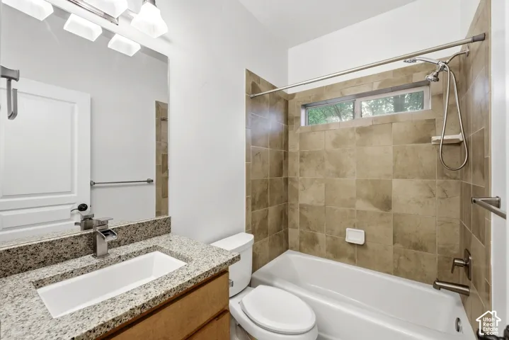 Bathroom featuring a single vanity with stone countertop, undermount sink, and a waterfall-style faucet