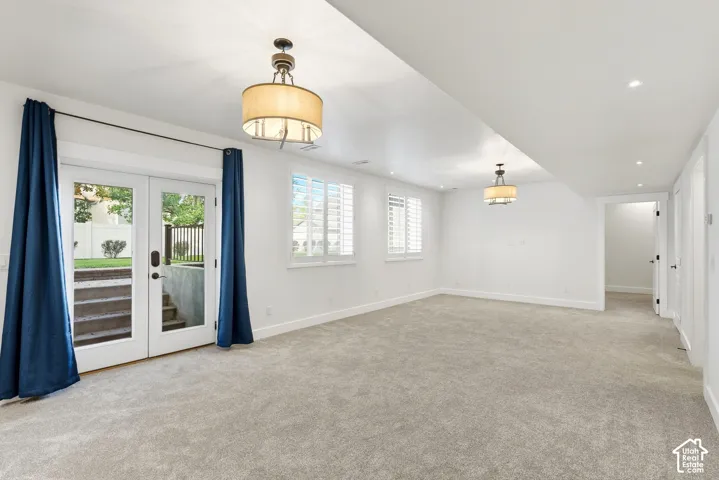 Wall-to-wall carpeting and white walls define this bright space, featuring white double doors with exterior access