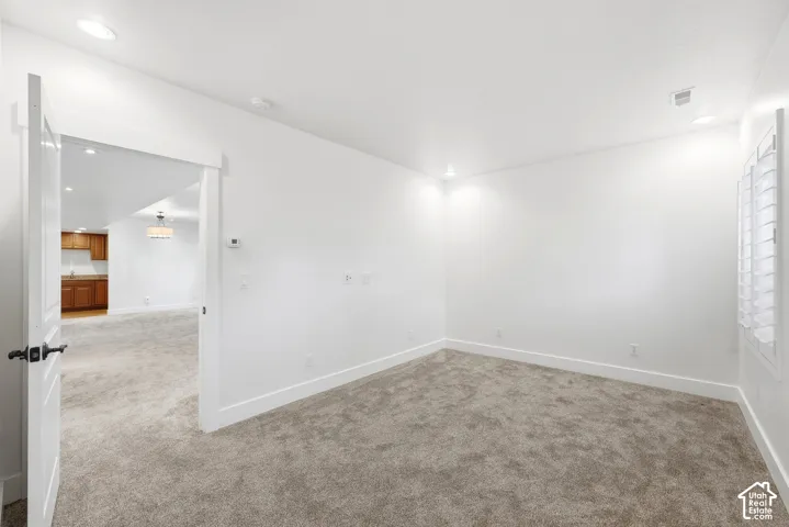 Carpeted room with white walls, recessed lighting, and window with white shutters