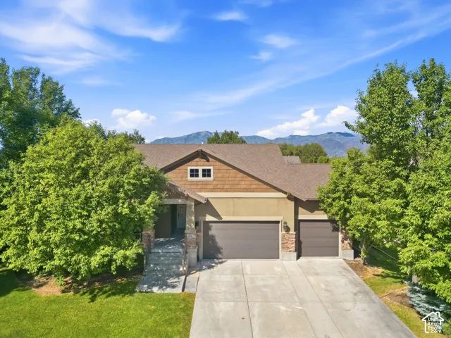 Two-car garage, stone columns, stucco exterior, shingle siding, and a concrete driveway
