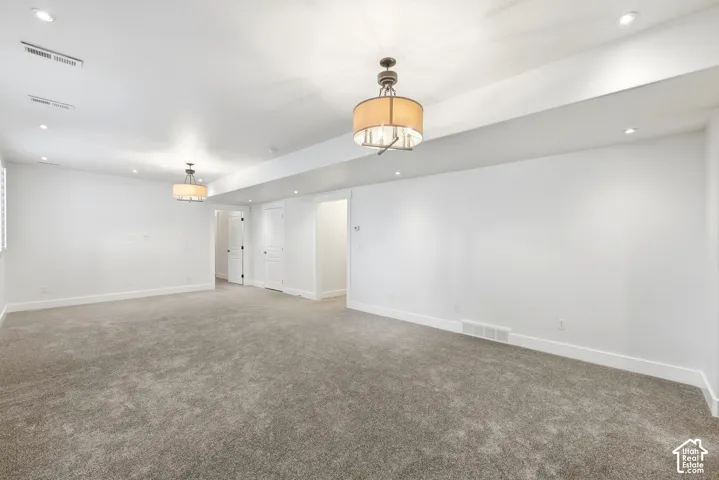 Spacious room featuring neutral carpeting, recessed lighting, and dual decorative ceiling fixtures