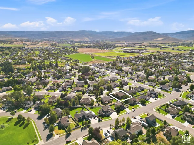 Residential neighborhood with mature trees, surrounded by distant mountains and open green spaces