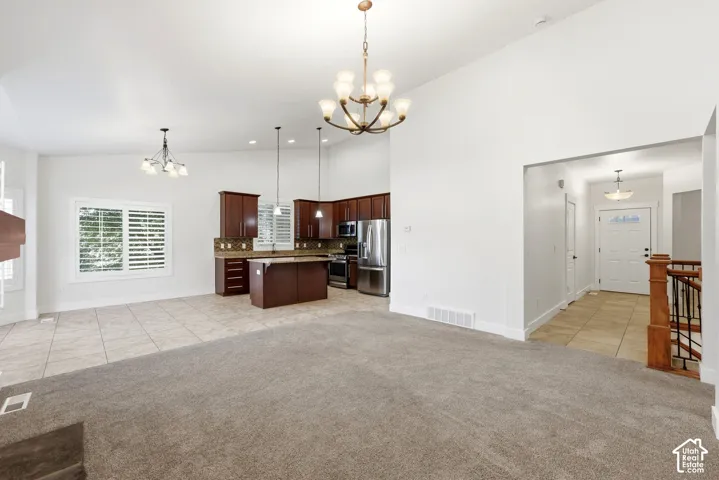 Vaulted ceilings with chandelier lighting, dark wood cabinetry, stainless steel appliances, and a kitchen island with bar seating