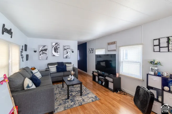 Wood-finish flooring throughout, white paneled walls, multiple windows with blinds, and recessed lighting