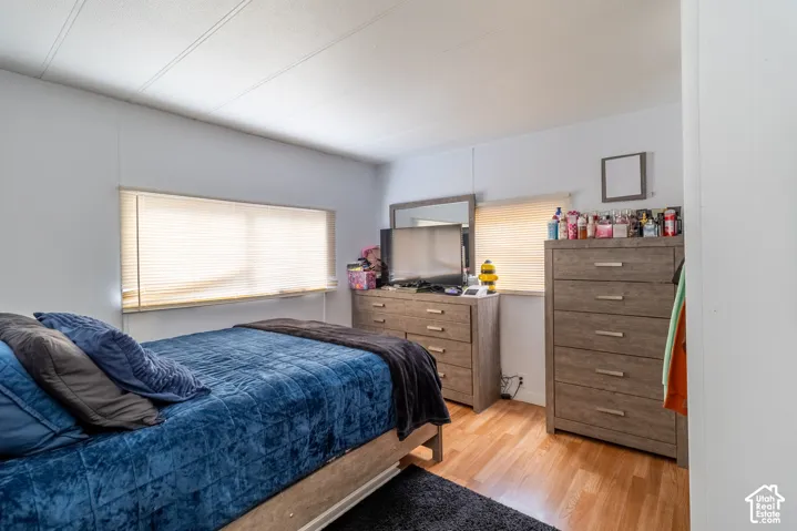 Wood-finish flooring, two windows with blinds, light-toned walls, and a flat white ceiling