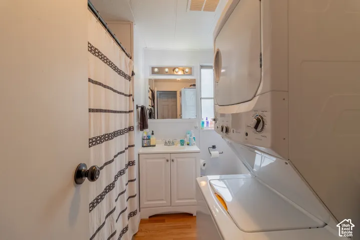 Bathroom featuring a built-in vanity with storage, a wall-mounted mirror, and a stacked washer and dryer
