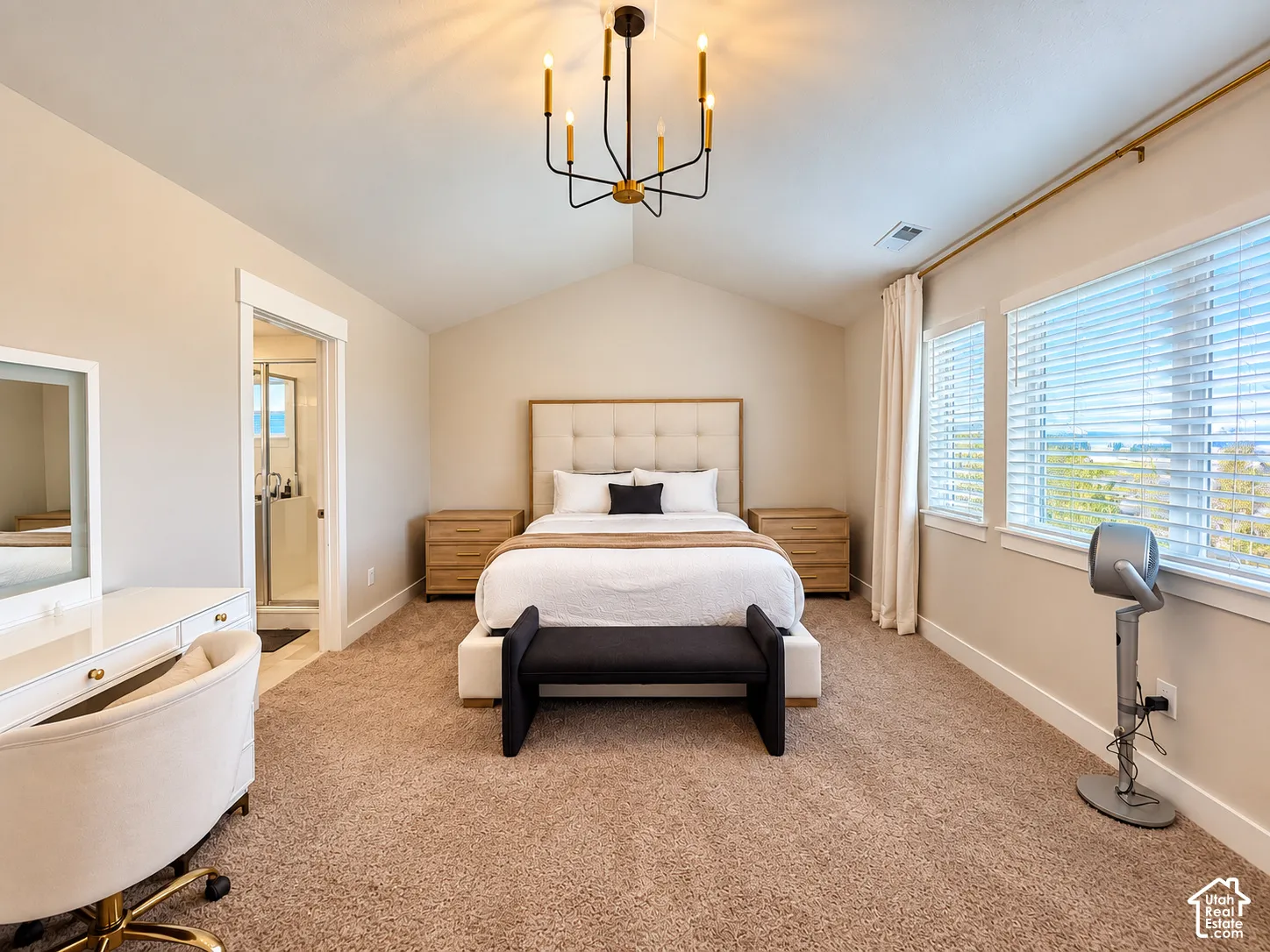 Vaulted ceiling with a chandelier, carpet flooring, multiple windows with blinds, and an attached bath with a glass-enclosed shower