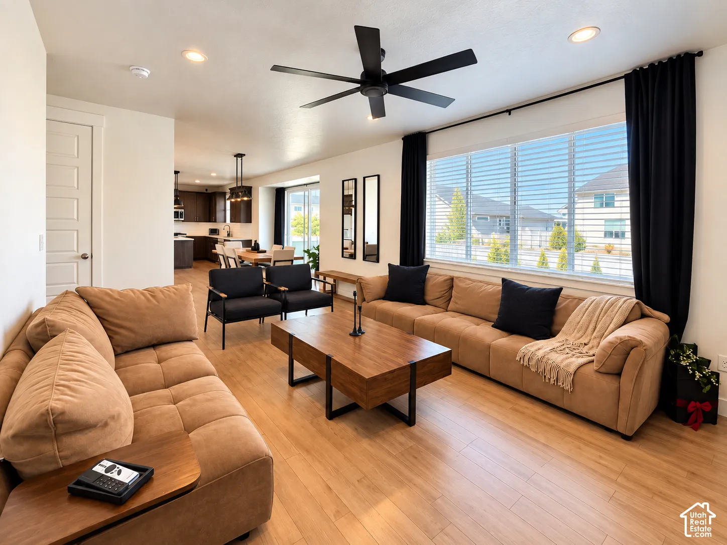 Open-concept living area with wood-finish flooring, recessed lighting, and a multi-pane window