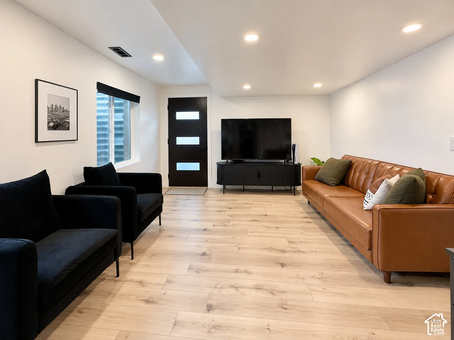 Recessed lighting, light wood-finish flooring, white walls, and a contemporary entry door with frosted glass panels