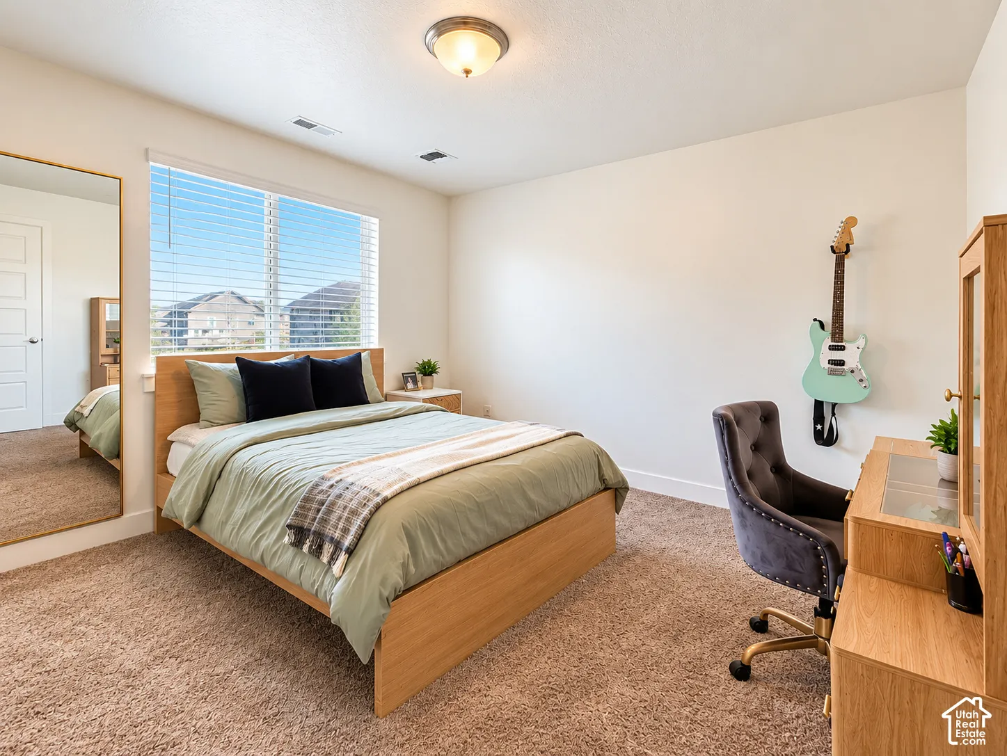 Recessed lighting, large window with blinds, light wood-finish bed frame, light wood-finish desk, and plush carpet