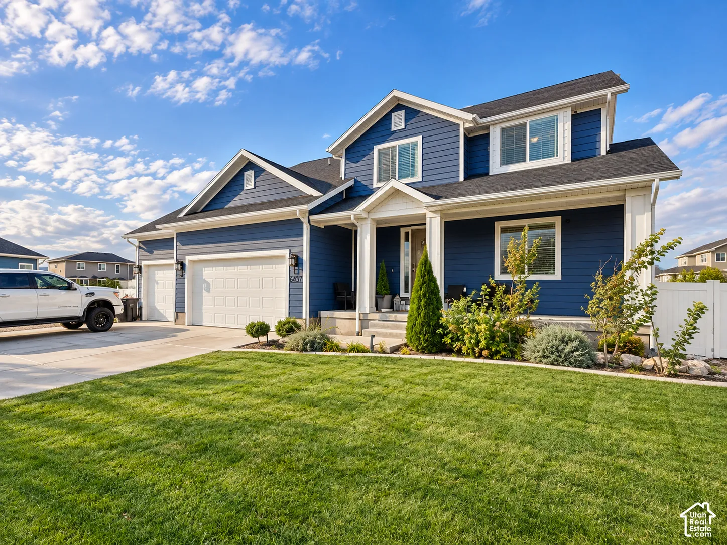 Two-story residence featuring blue siding, white trim, a dark shingle roof, and a two-car garage with white doors