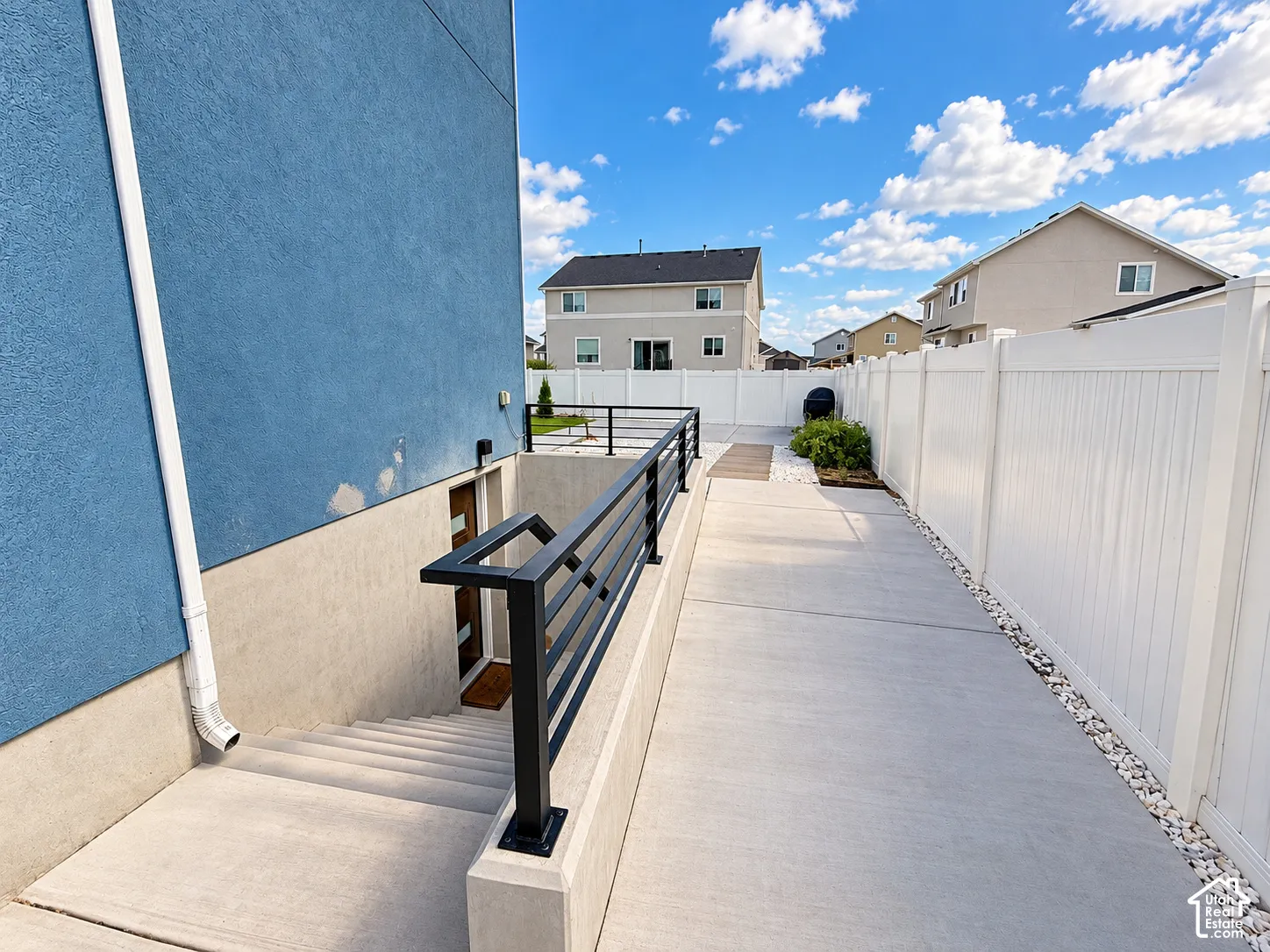Concrete walkway bordered by white vinyl fencing