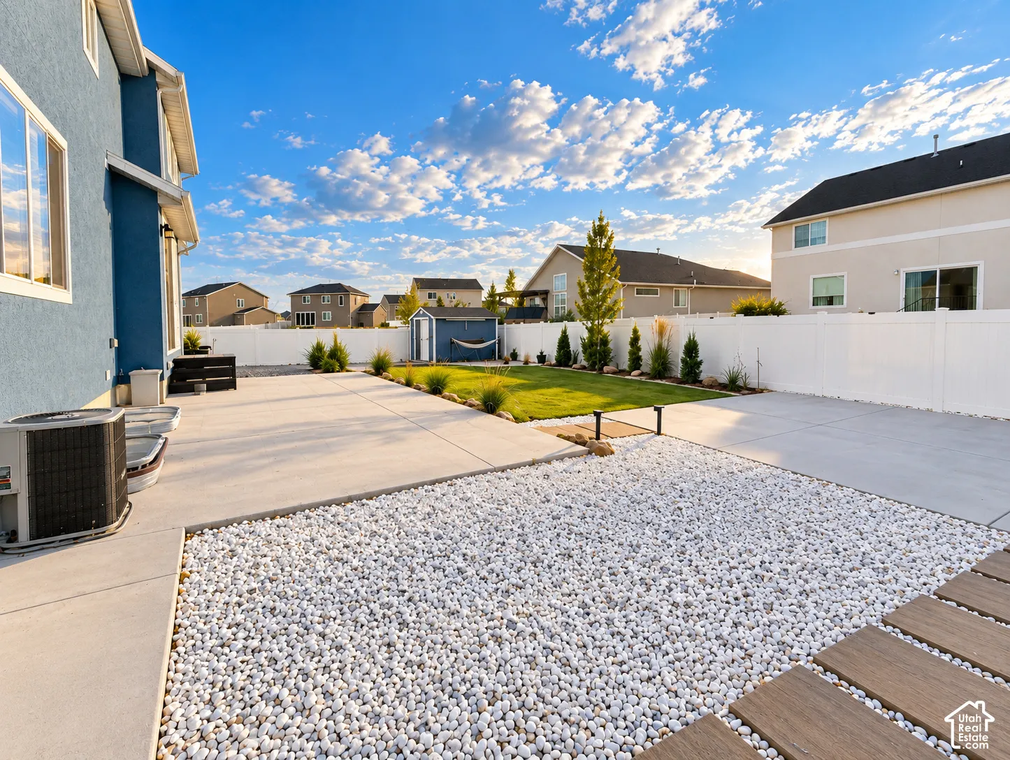 Expansive concrete patio with white pebble landscaping and wood-look stepping stones
