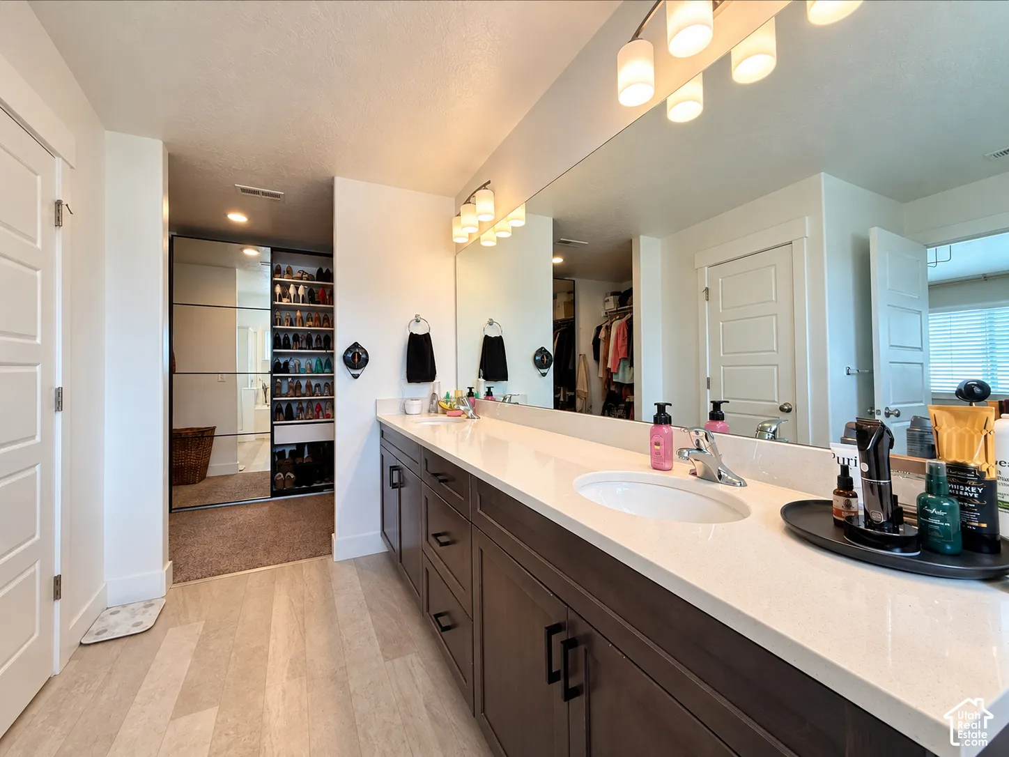 Elongated vanity with dual sinks, extensive counter space, and dark wood-finish cabinetry