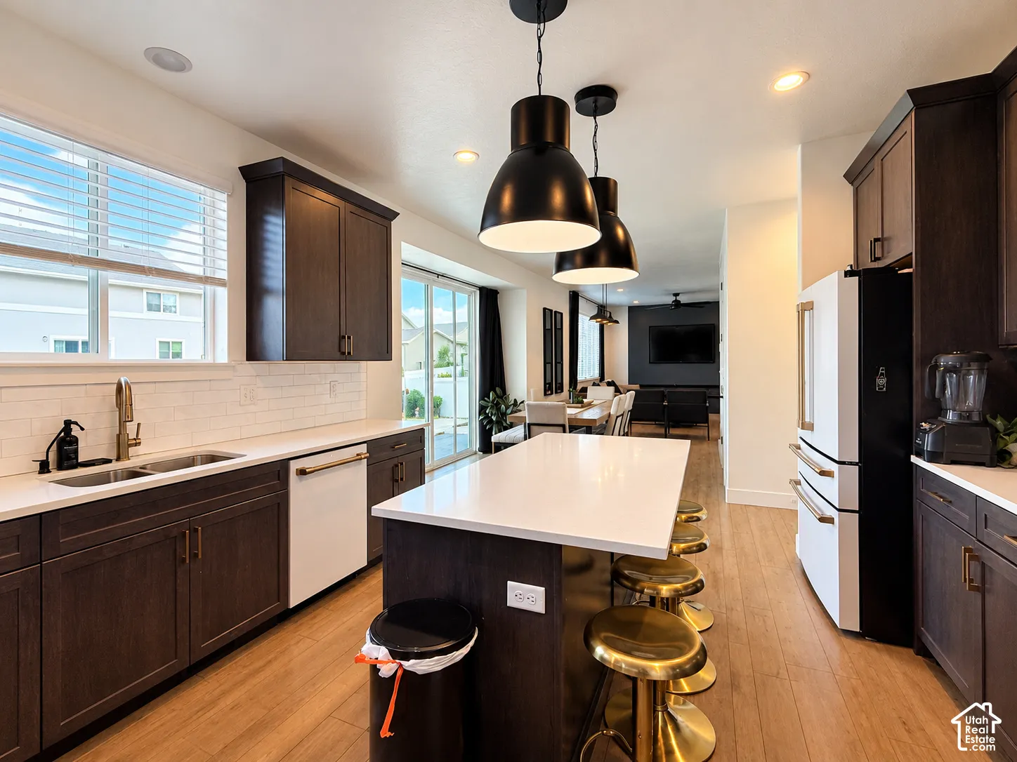 Kitchen featuring wood-finish flooring, dark wood cabinetry, a white subway tile backsplash, and a large central island with a white countertop