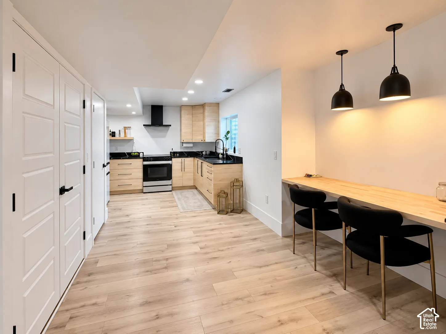 Kitchen with light wood-finish cabinetry, black countertops, and stainless steel appliances