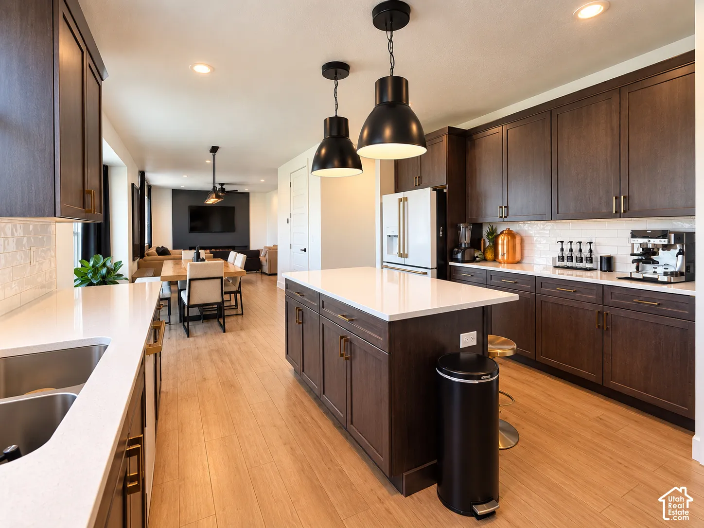 Well-appointed kitchen featuring wood-finish flooring, dark wood cabinetry with gold-tone hardware, white countertops, and a white subway tile backsplash