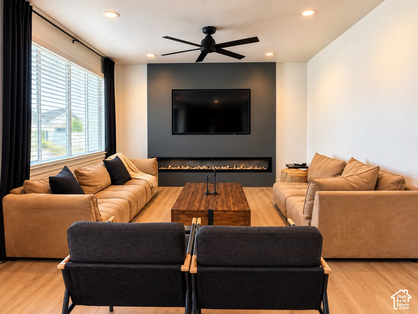 Recessed lighting, wood-finish flooring, and a linear fireplace with a dark accent wall