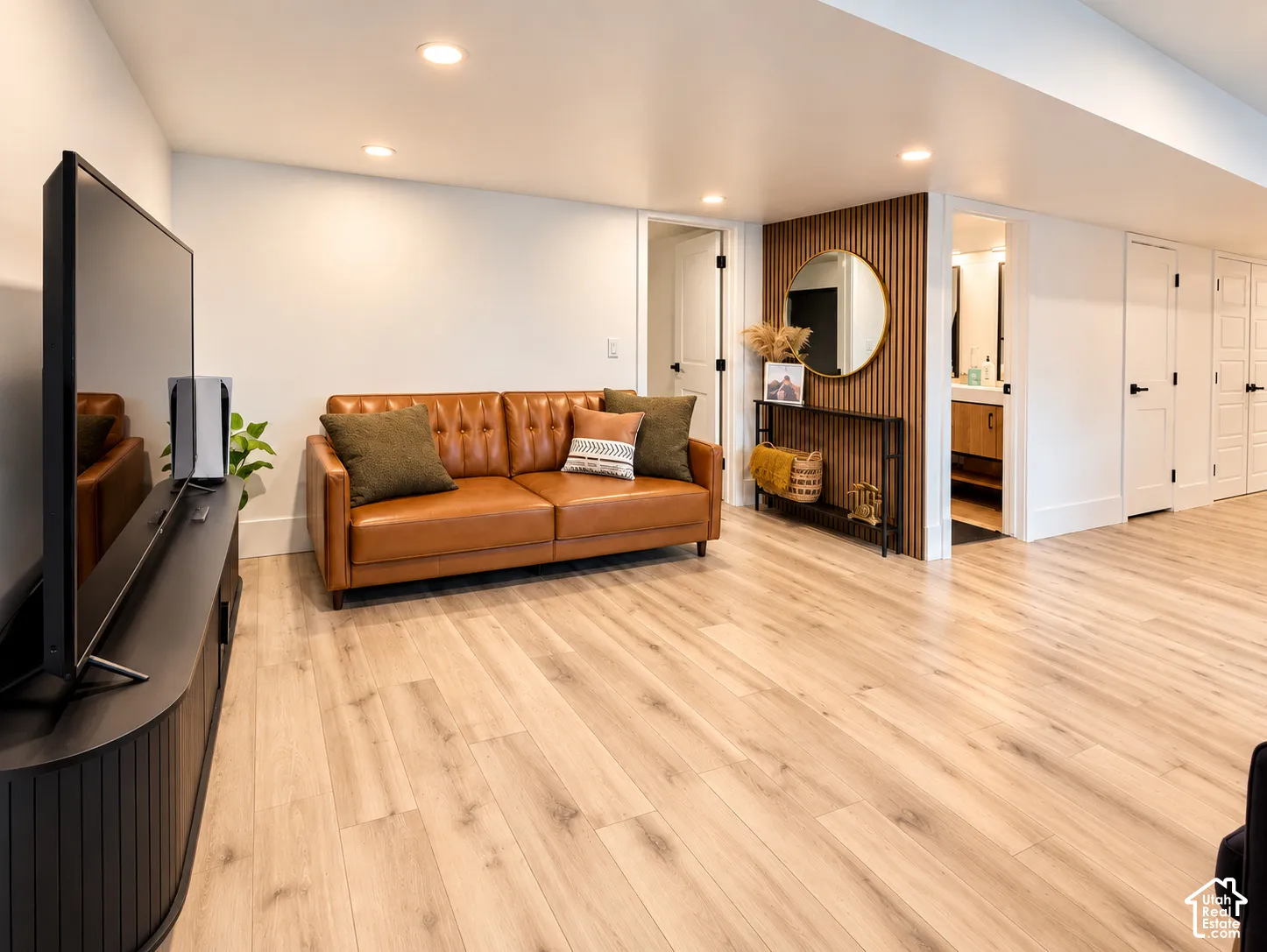 Recessed lighting illuminates the space, featuring light wood-finish flooring and a white wall finish