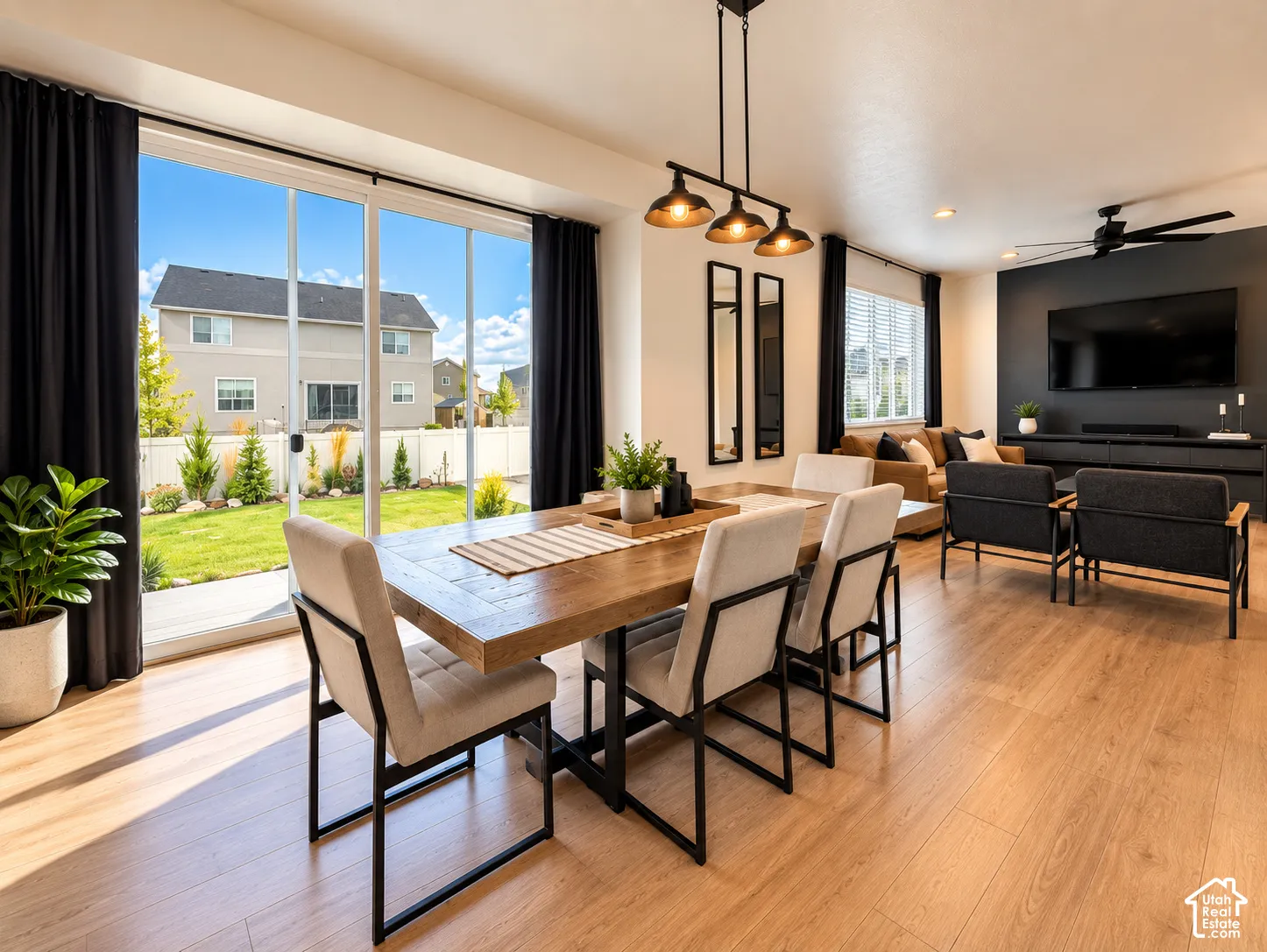 Open-concept living area with wood-finish flooring, a linear pendant light fixture, and a large sliding glass door