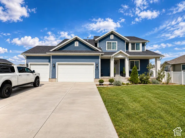 Two-story residence featuring a dark blue facade, white trim, a covered porch, a three-car garage, and a concrete driveway