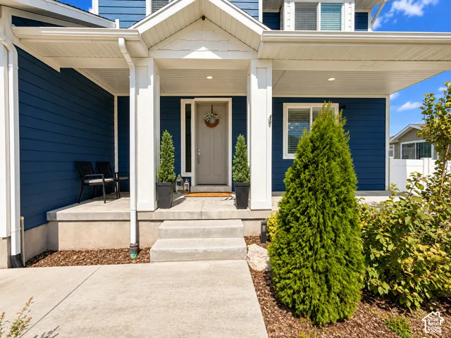 Inviting front porch featuring a prominent entryway, concrete steps, and blue horizontal siding