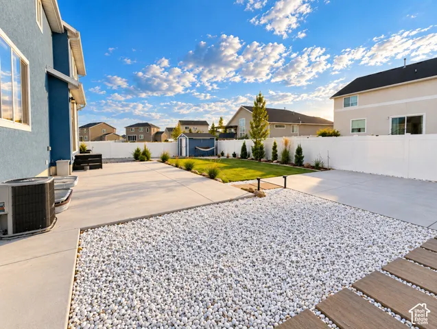 Expansive concrete patio with white pebble landscaping and wood-look stepping stones