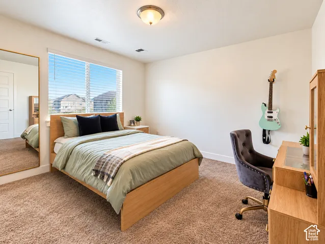 Recessed lighting, large window with blinds, light wood-finish bed frame, light wood-finish desk, and plush carpet