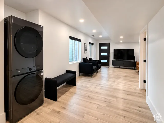 Stacked washer and dryer unit, wood-finish flooring, recessed lighting, and a modern exterior door with frosted glass inserts