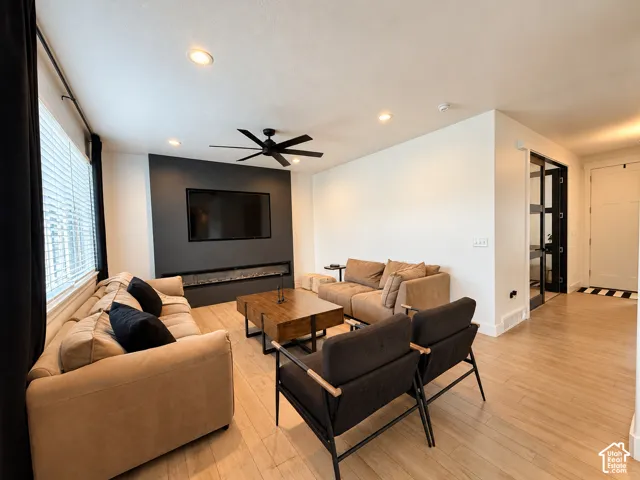 Open-concept living space with light wood-finish flooring, recessed lighting, and a contemporary ceiling fan