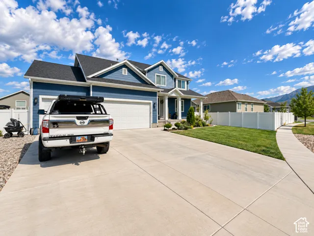 Blue siding exterior with white trim, two-car garage, concrete driveway, and front landscaping