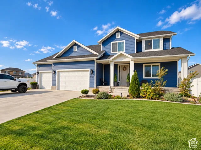 Two-story property featuring a blue siding exterior, a two-car garage, and a covered front porch with white columns