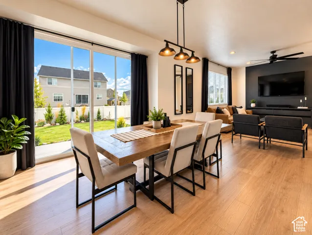 Open-concept living area with wood-finish flooring, a linear pendant light fixture, and a large sliding glass door